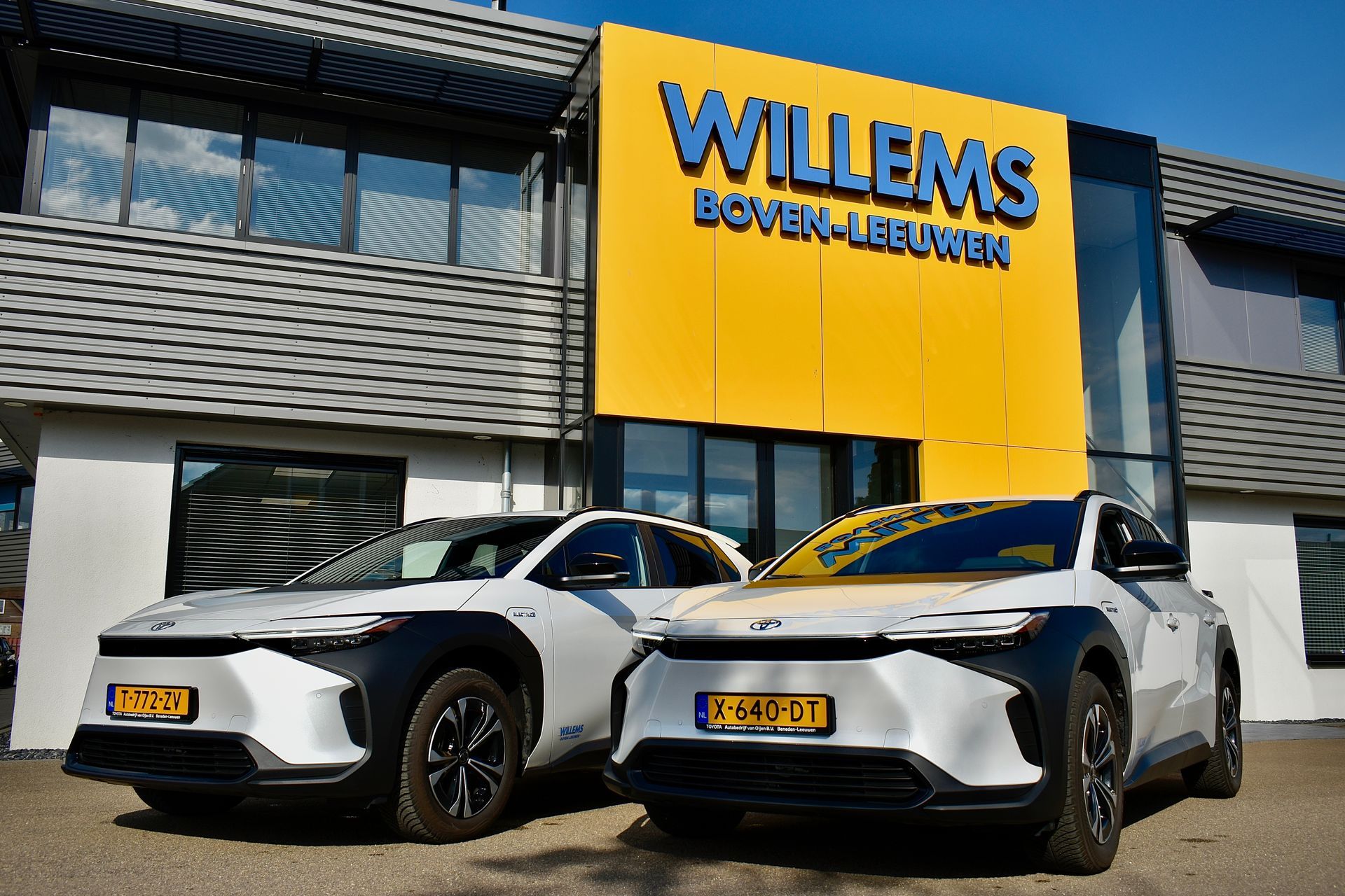 Er staan ​​twee auto's geparkeerd voor een gebouw waar willems staat