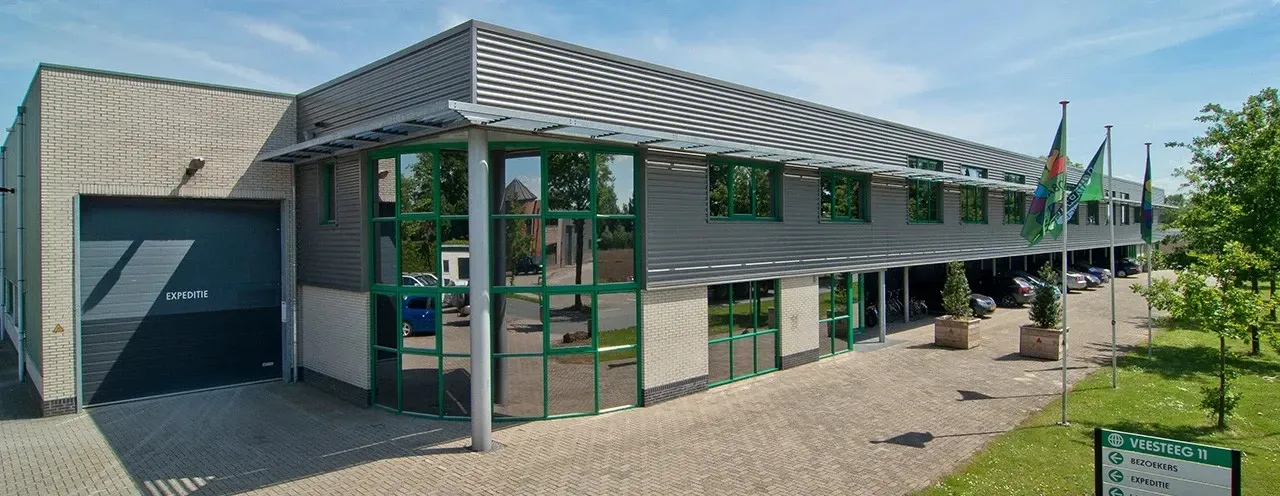 Een groot gebouw met veel ramen en een gestreept dak Door Willems Boven-Leeuwen.