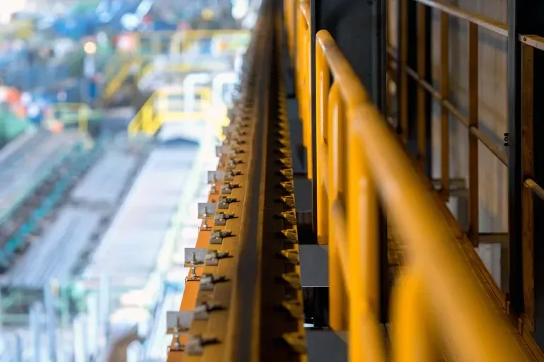 Een close-up van een gele reling in een fabriek.