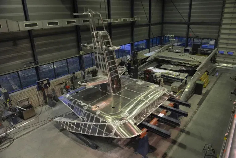 In een fabriek wordt een grote roestvrijstalen boot gebouwd. 