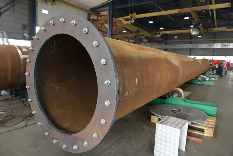 Een grote metalen pijp zit in een fabriek. Door Willems Boven-Leeuwen.