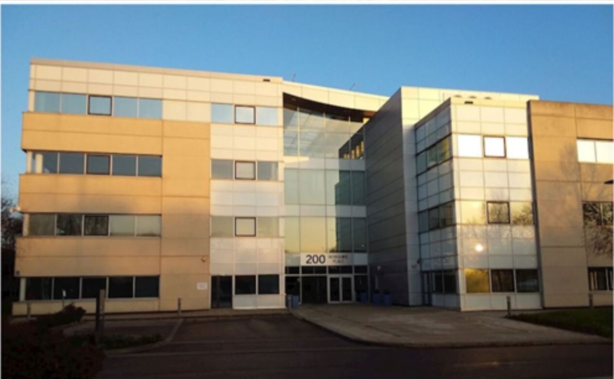 Office building with light tan and gray panels, glass entrance, and the number 200 above the door.