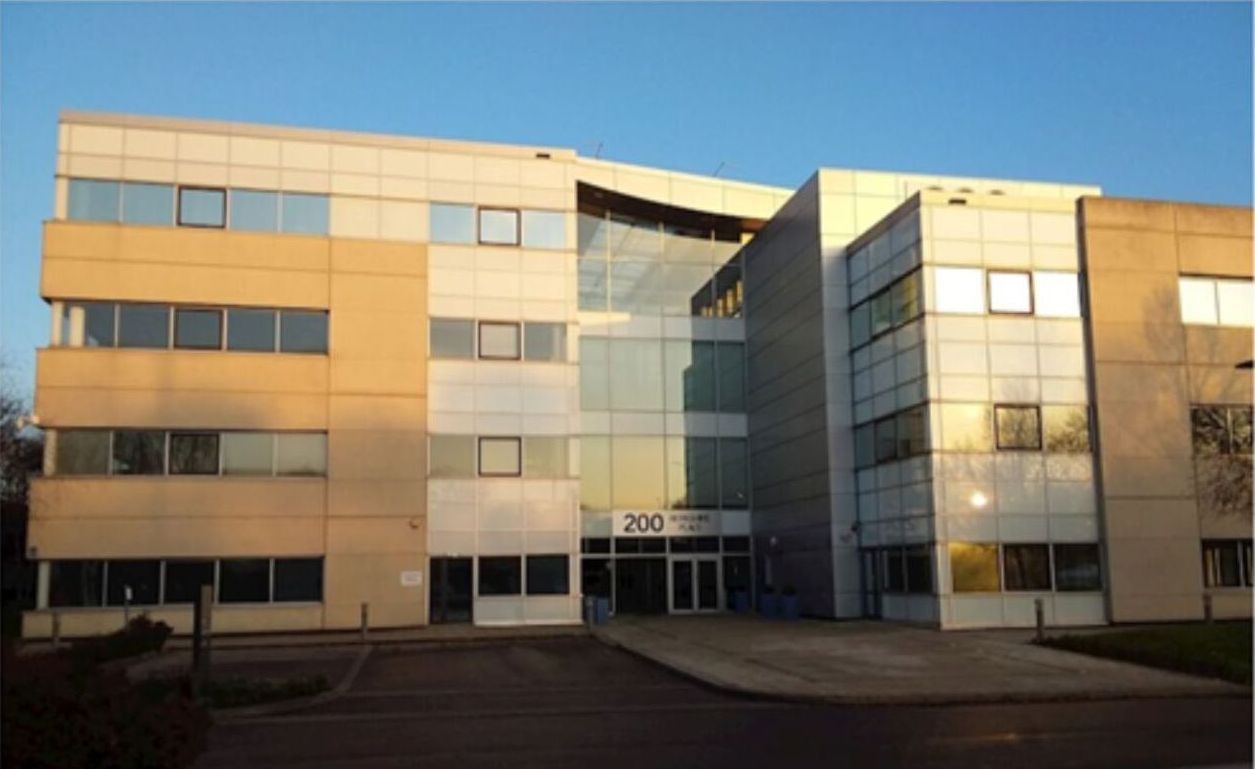 The sun shines on a large office building with multiple windows and a cladded facade.