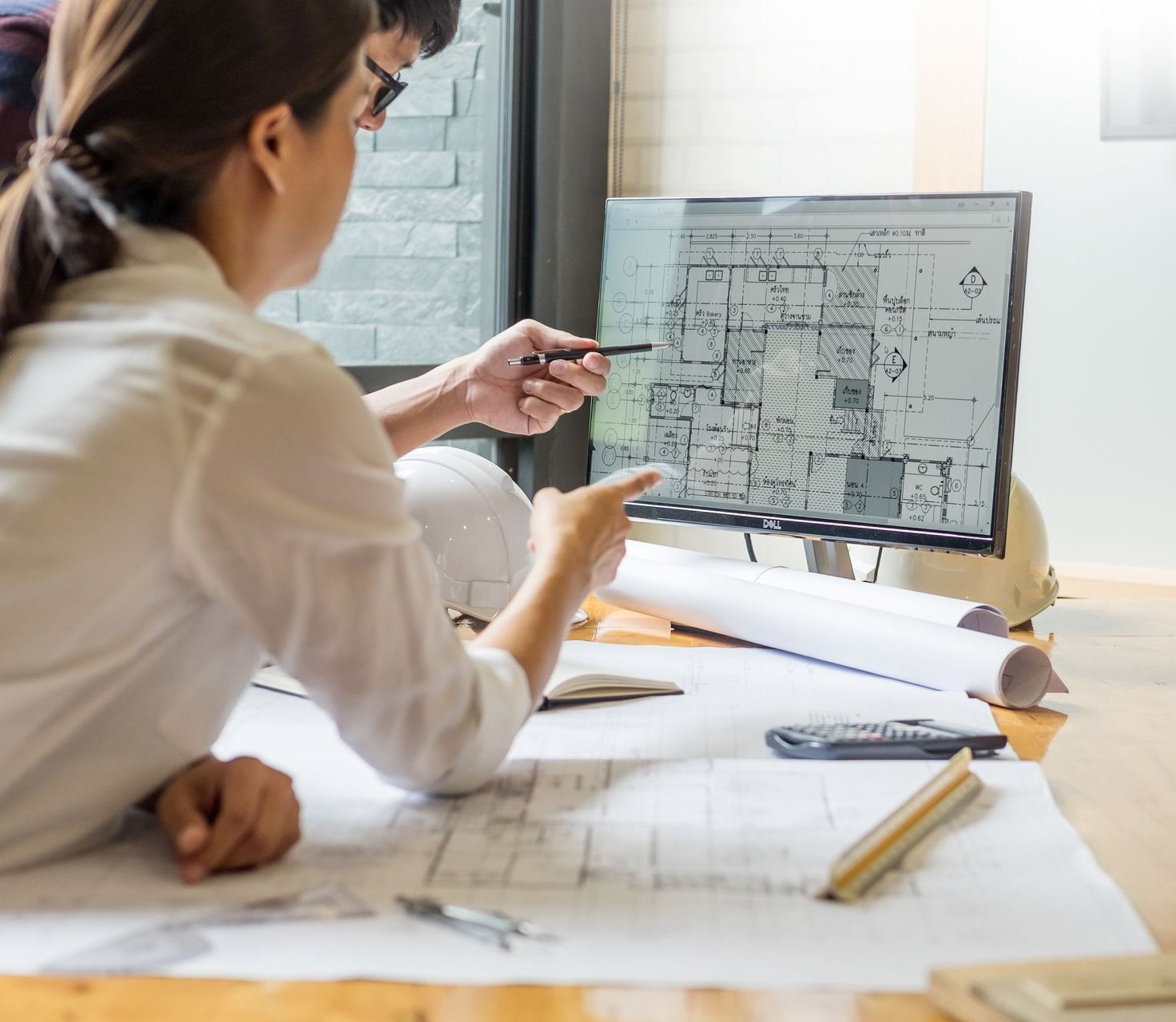 a man and a woman are looking at a floor plan on a dell computer