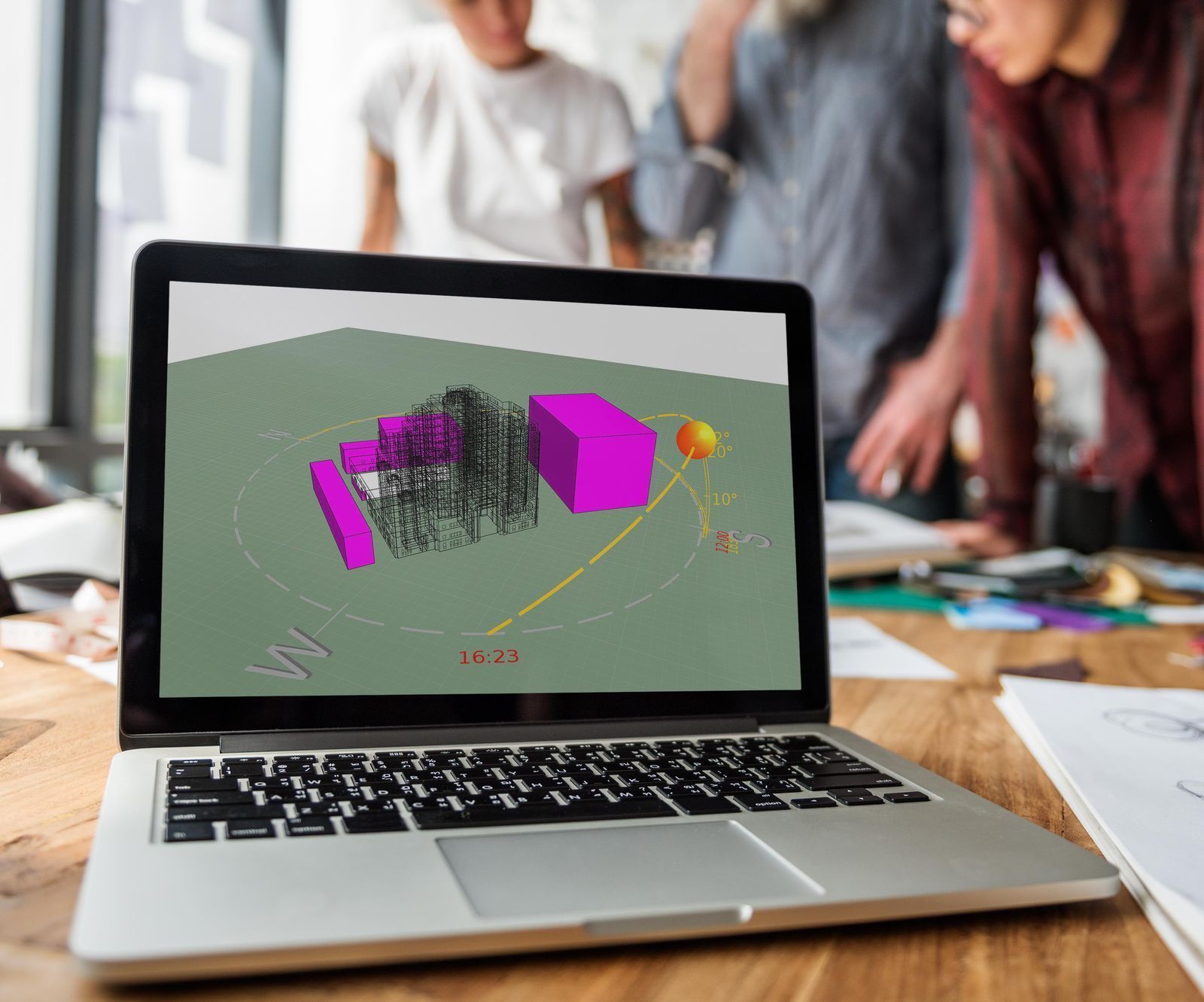 Laptop displaying 3D building model, viewed by group of people.
