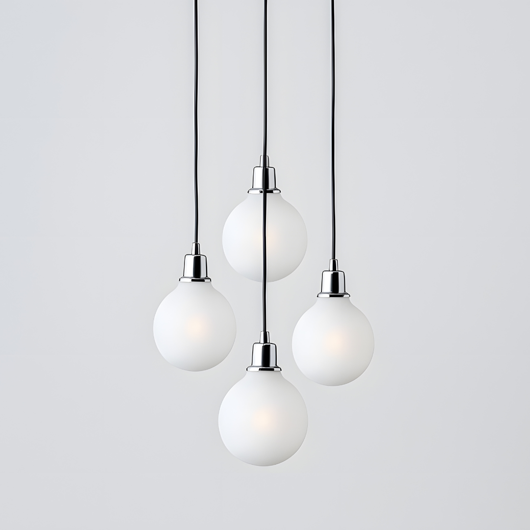 Four white globe pendant lights hanging from black cords against a white backdrop.