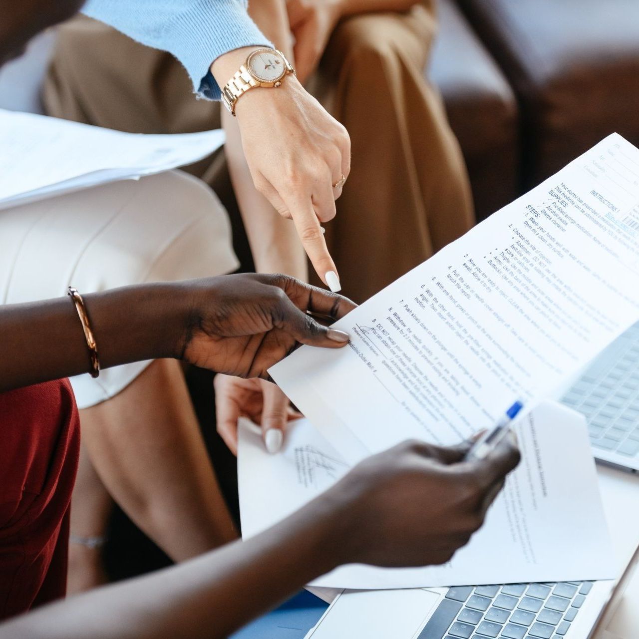 Hands pointing at and holding documents, possibly a business meeting.