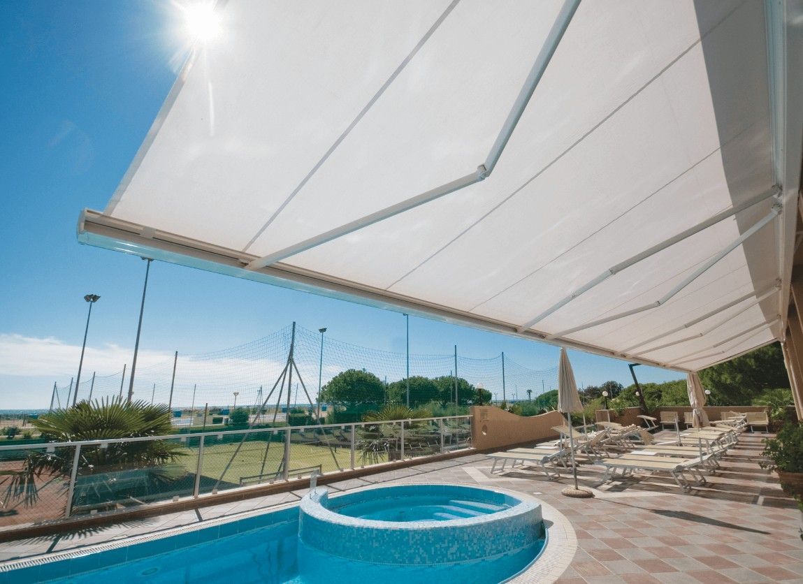 White awning shading a pool and patio on a sunny day.