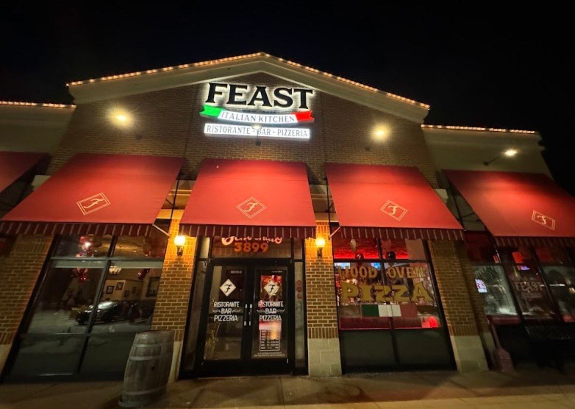 Feast Italian Kitchen restaurant exterior at night with red awnings and illuminated sign.