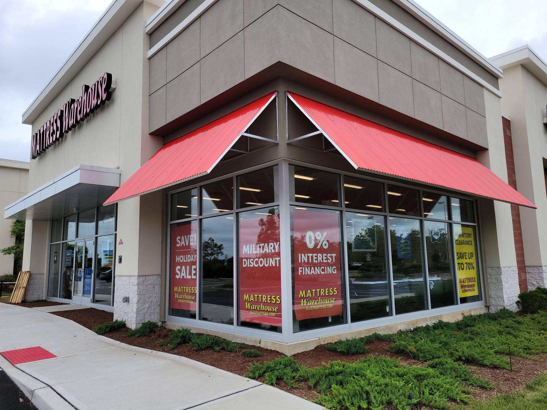 Storefront with red awning, large windows, and sale signs.