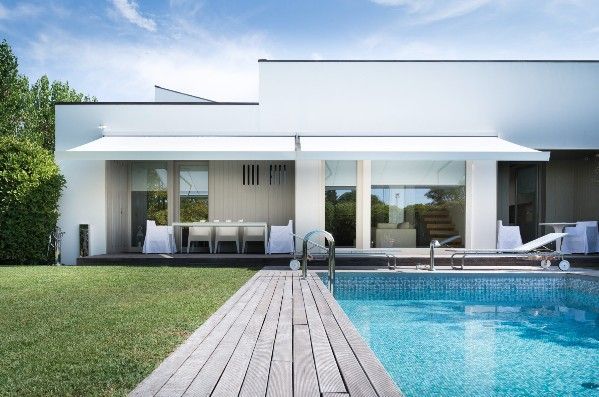 White modern house with pool and wooden walkway.