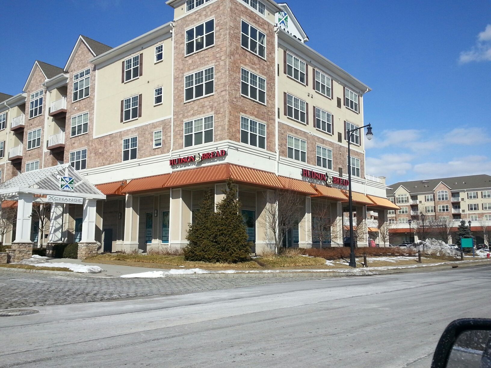 Multi-story brick building with awnings over a ground-floor storefront, set against a bright blue sky.