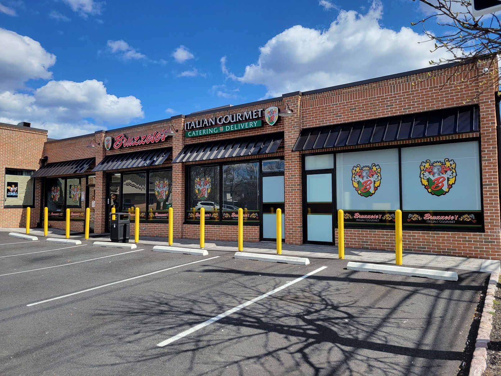 Exterior view of a brick commercial building with three storefronts under awnings. Sunny day, blue sky.