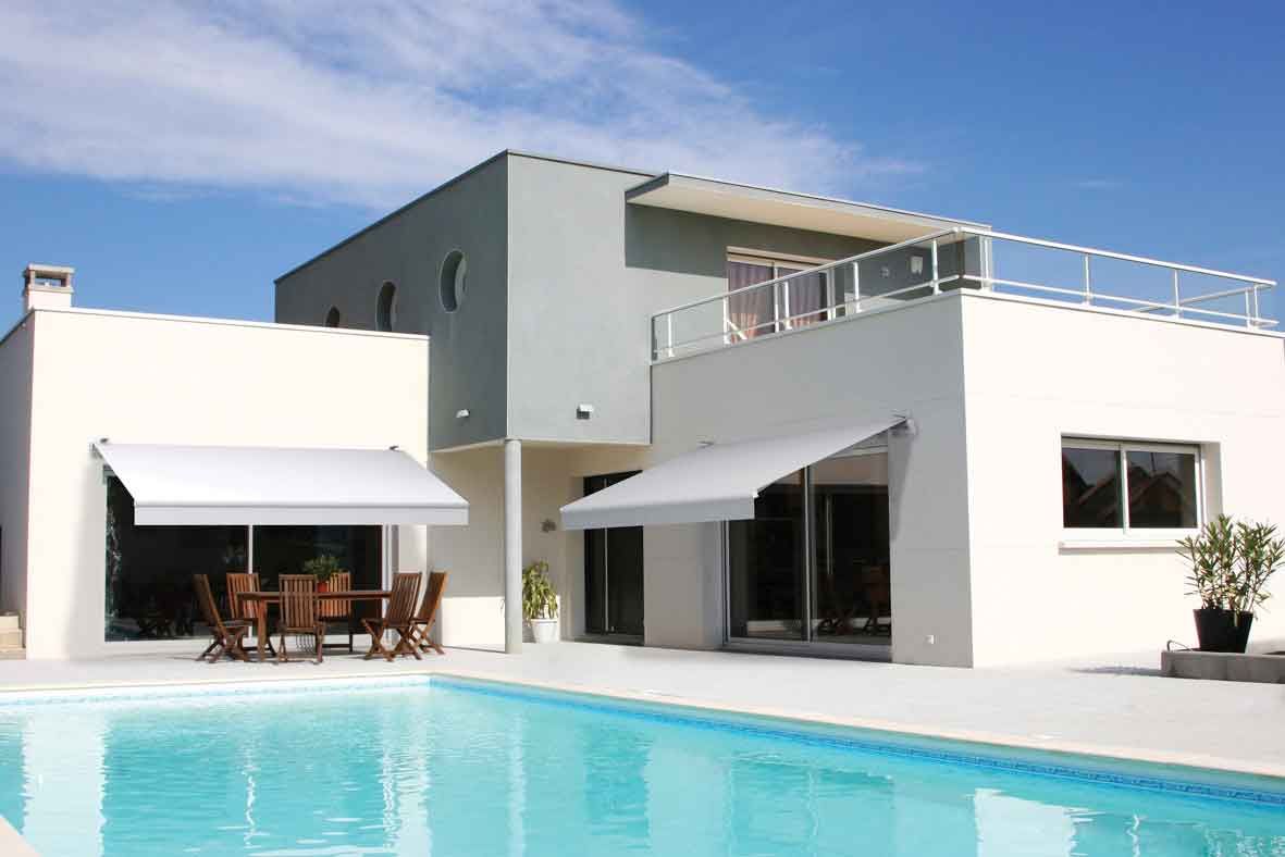 Modern white house with a pool, awnings, and a blue sky.