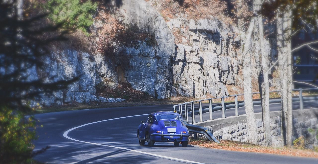 A blue car is driving down a curvy road.