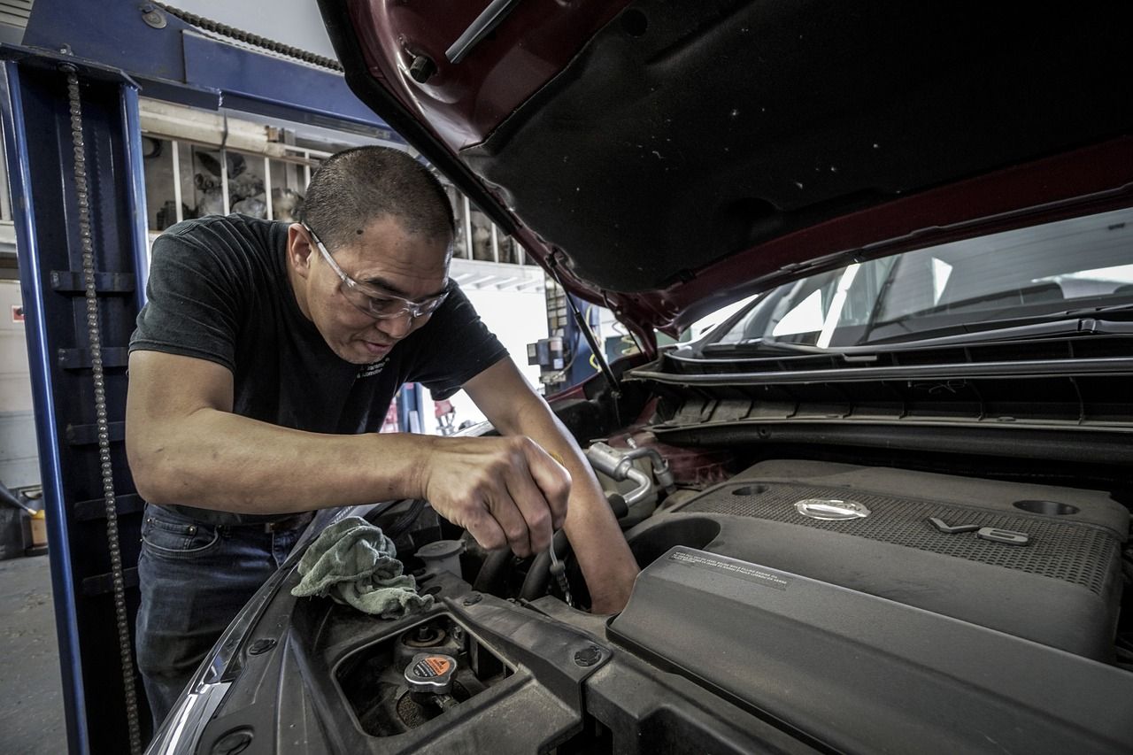 A man is working on the engine of a car in a garage.