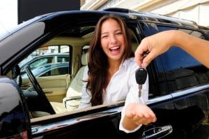 A woman is sitting in a car holding a car key.