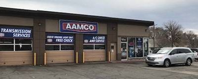 A car is parked in front of a transmission service shop.