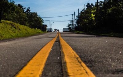 A car is driving down a road with two yellow lines on it.