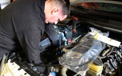 A man is working on the engine of a car.