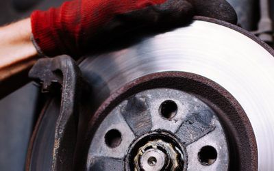 A person wearing red gloves is working on a brake disc.