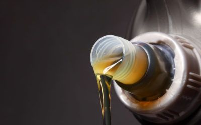 A close up of a bottle of oil being poured into a car.