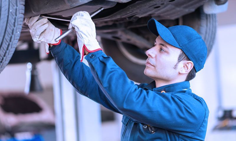 A man is working under a car with a wrench.
