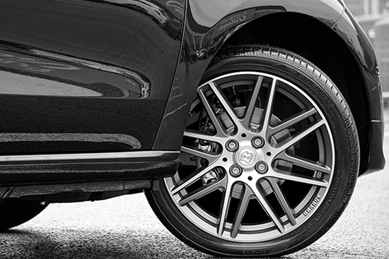 A black and white photo of a car with a flat tire.