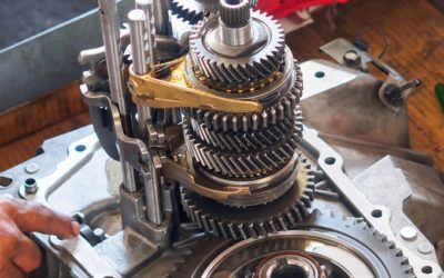 A person is working on a gearbox on a wooden table.