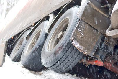 A truck is stuck in the snow on the side of the road.