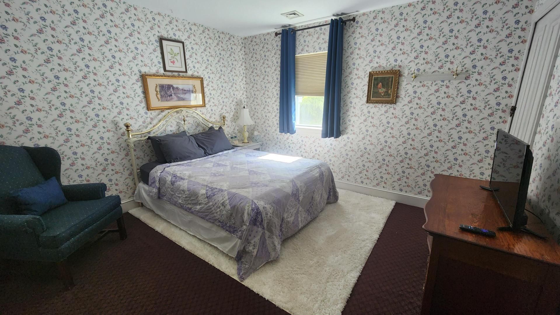 A bedroom with a bed , chair , dresser and television.