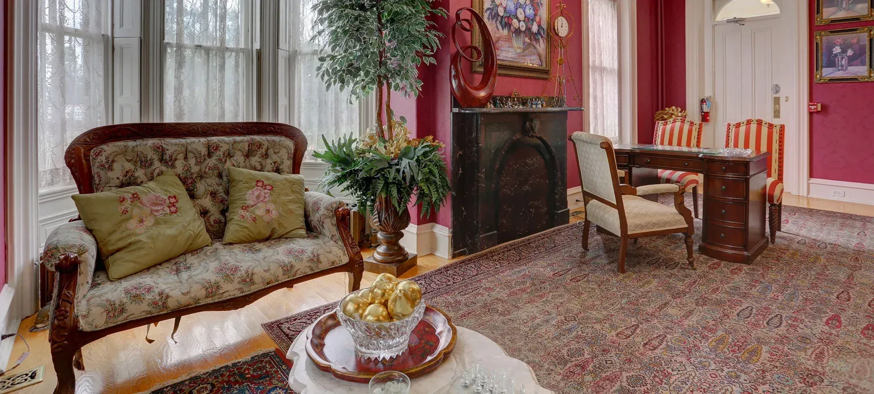 A living room with a couch , fireplace , chairs and a desk.
