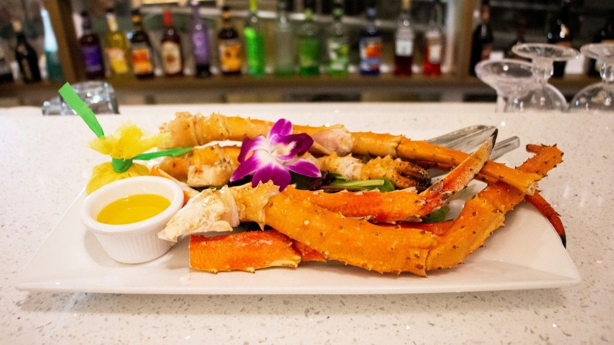 A white plate topped with crab legs and sauce on a counter.