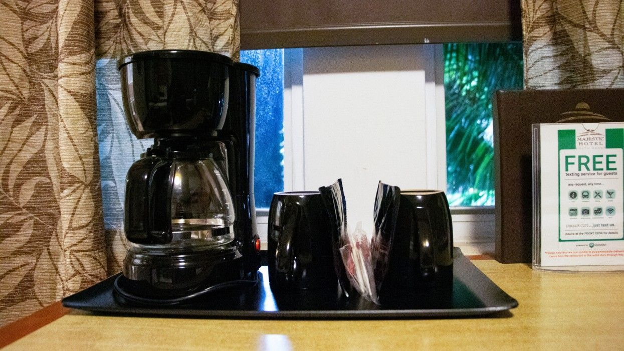 A coffee maker and cups on a tray next to a free sign