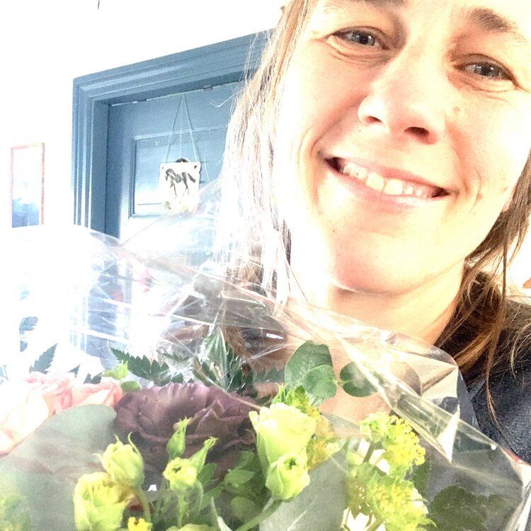 en kvinde smiler, mens hun holder en buket blomster