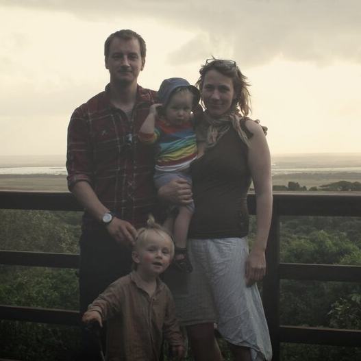 en familie poserer til et billede foran et plankeværk
