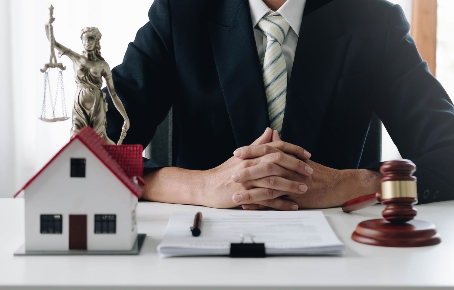 close-up photo of lawyer, wooden hammer and small wooden house on the table in law office