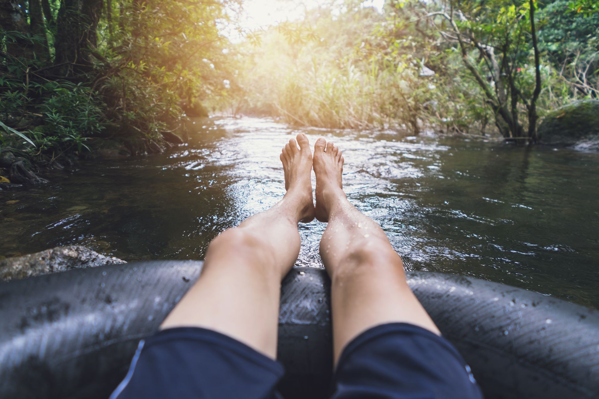 a person's feet are sticking out of a tube in a river