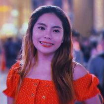 Smiling person in an orange off-shoulder top at a softly lit evening event