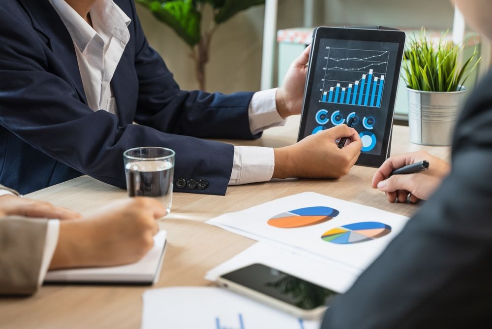 Business meeting with people reviewing charts on a tablet and paper graphs at a conference table