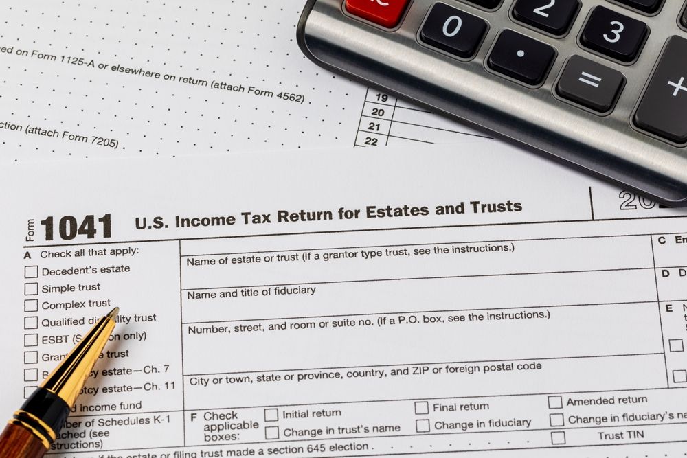 IRS Form 1041 with a pencil and calculator on a desk