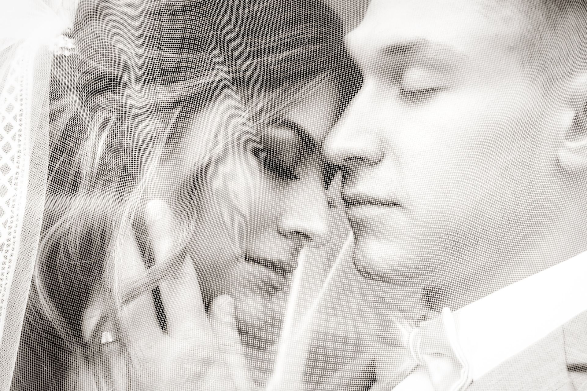Bride and groom, eyes closed, faces touching, overlaid with textured lines in black and white.