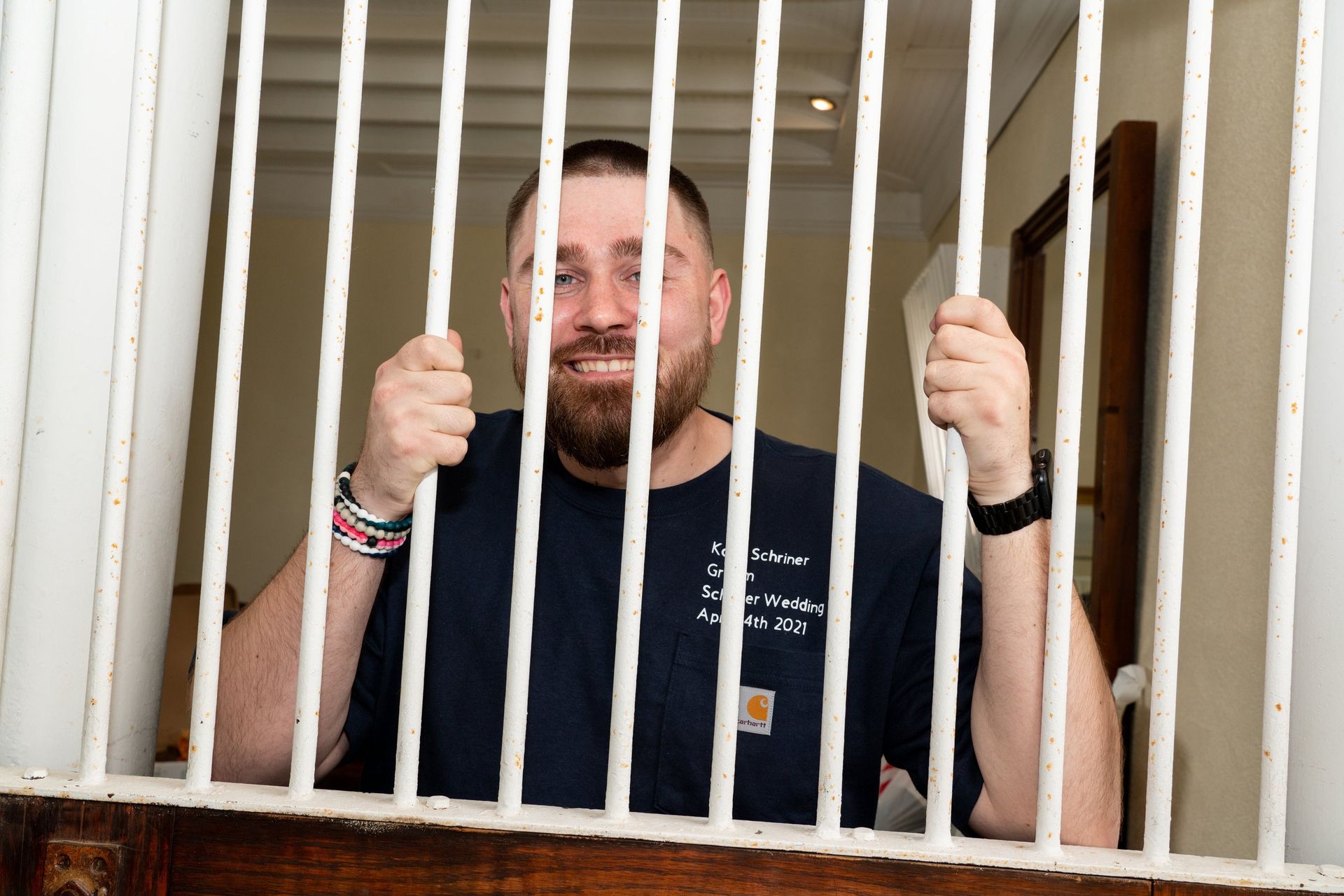 Man with beard smiling, holding bars, inside a room.