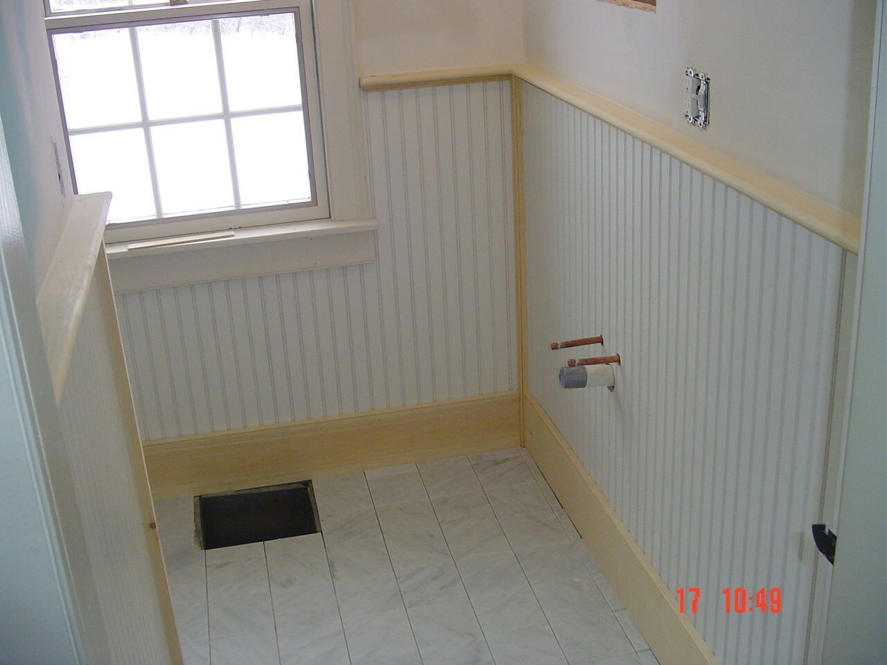A bathroom with white paneling and a window