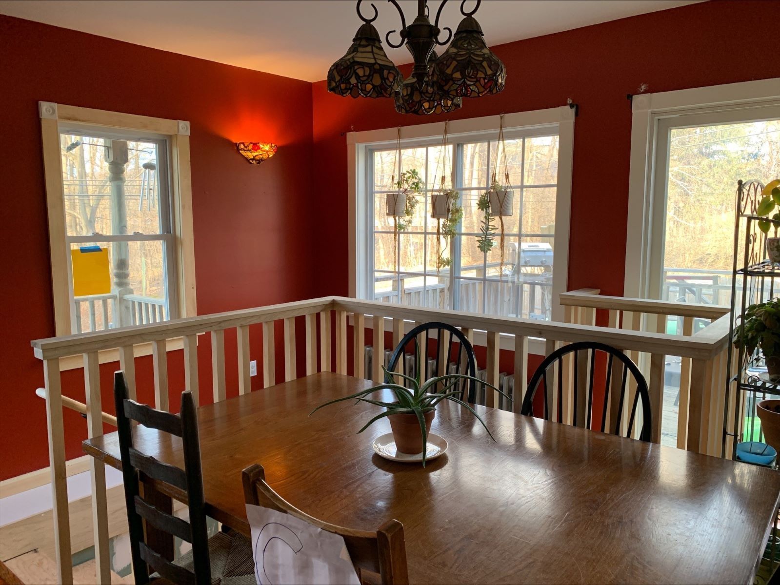 A dining room with a wooden table and chairs and a chandelier.