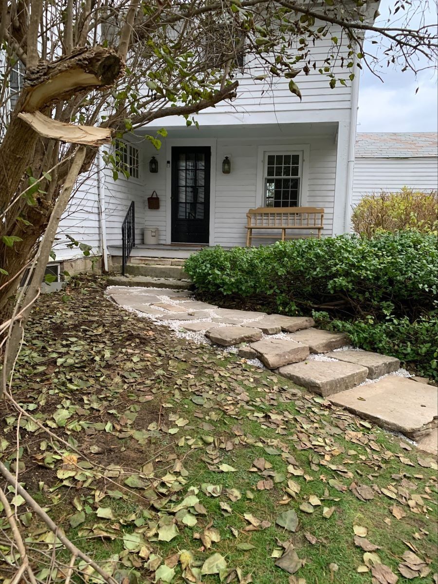 A white house with a stone walkway leading to the front door.