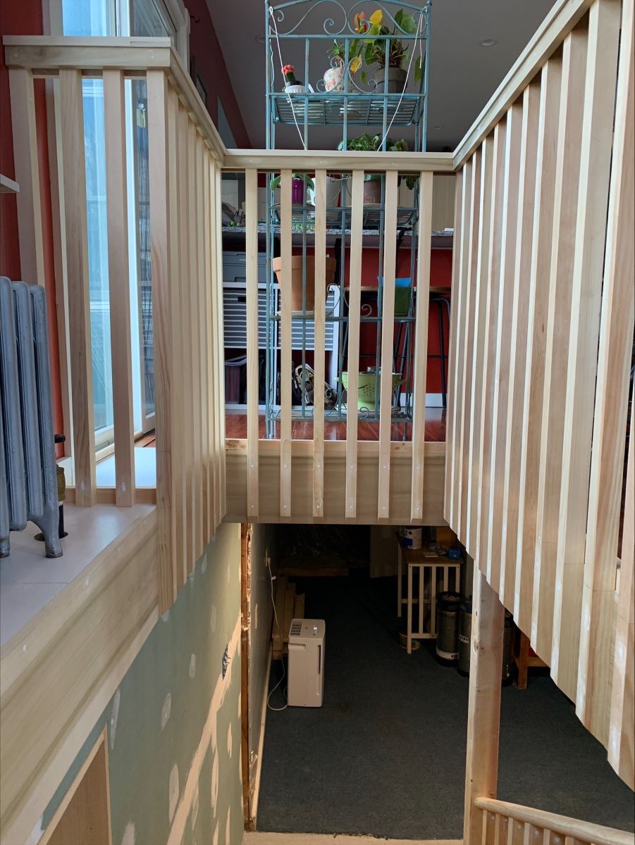 A staircase with a wooden railing leading up to the second floor installation