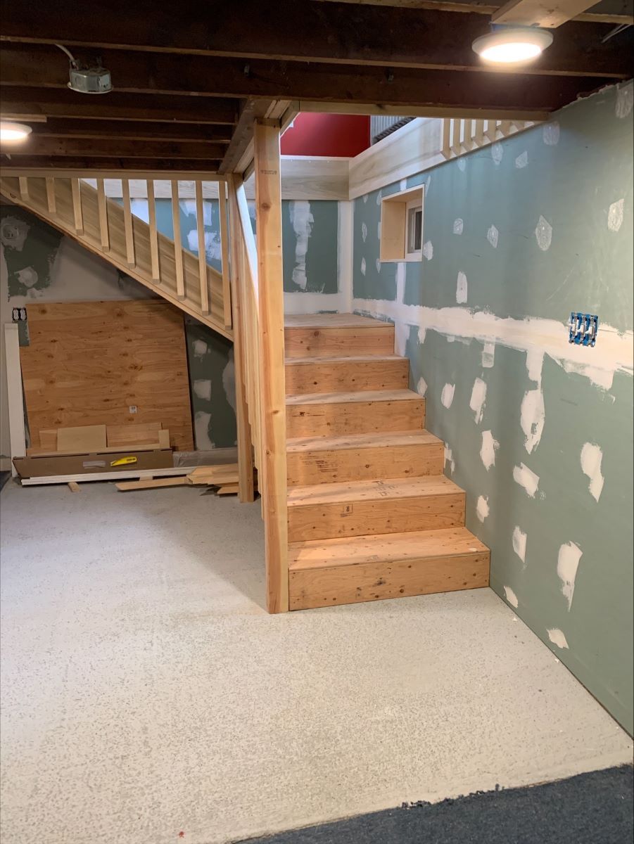 A basement with wooden stairs and a wooden railing.