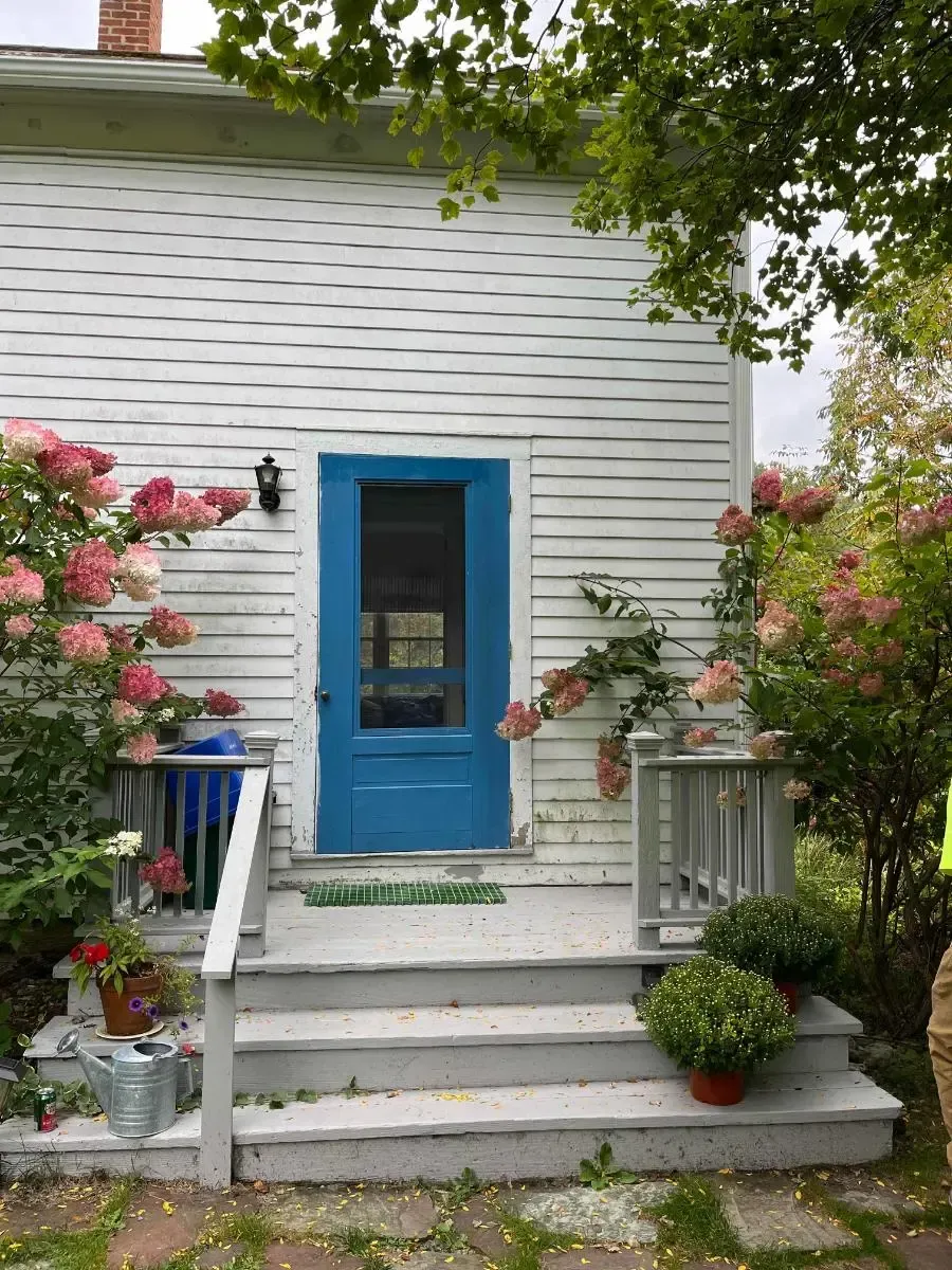 A white house with a blue door and stairs