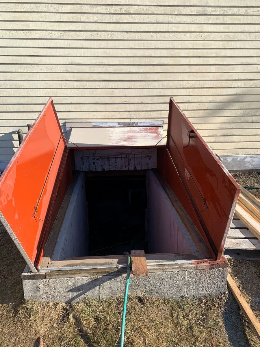 A basement with a red door and a hose attached to it.